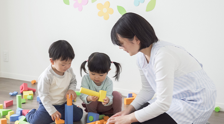 積み木で遊ぶ子ども2人と保育者