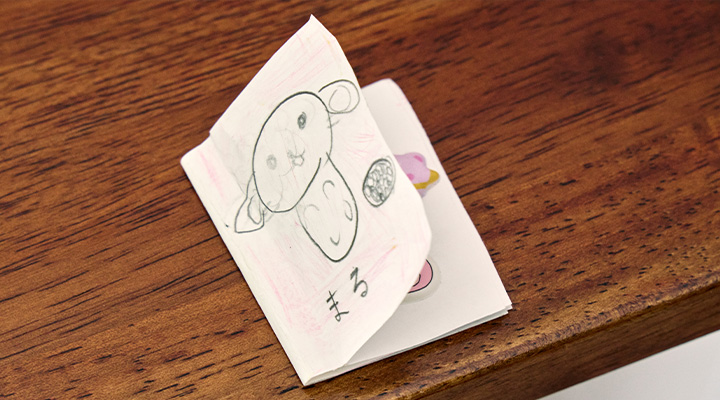 常連の子どもが風間さんのために作ってくれたシール帳。表紙に愛犬・マルの絵が描かれている